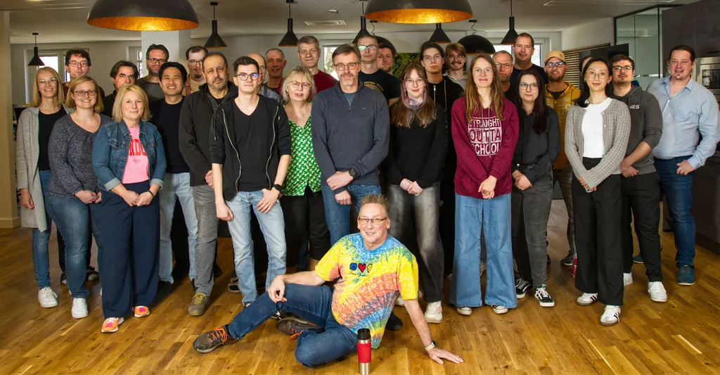 The cycos team standing (and one sitting) together on the lounge of the office